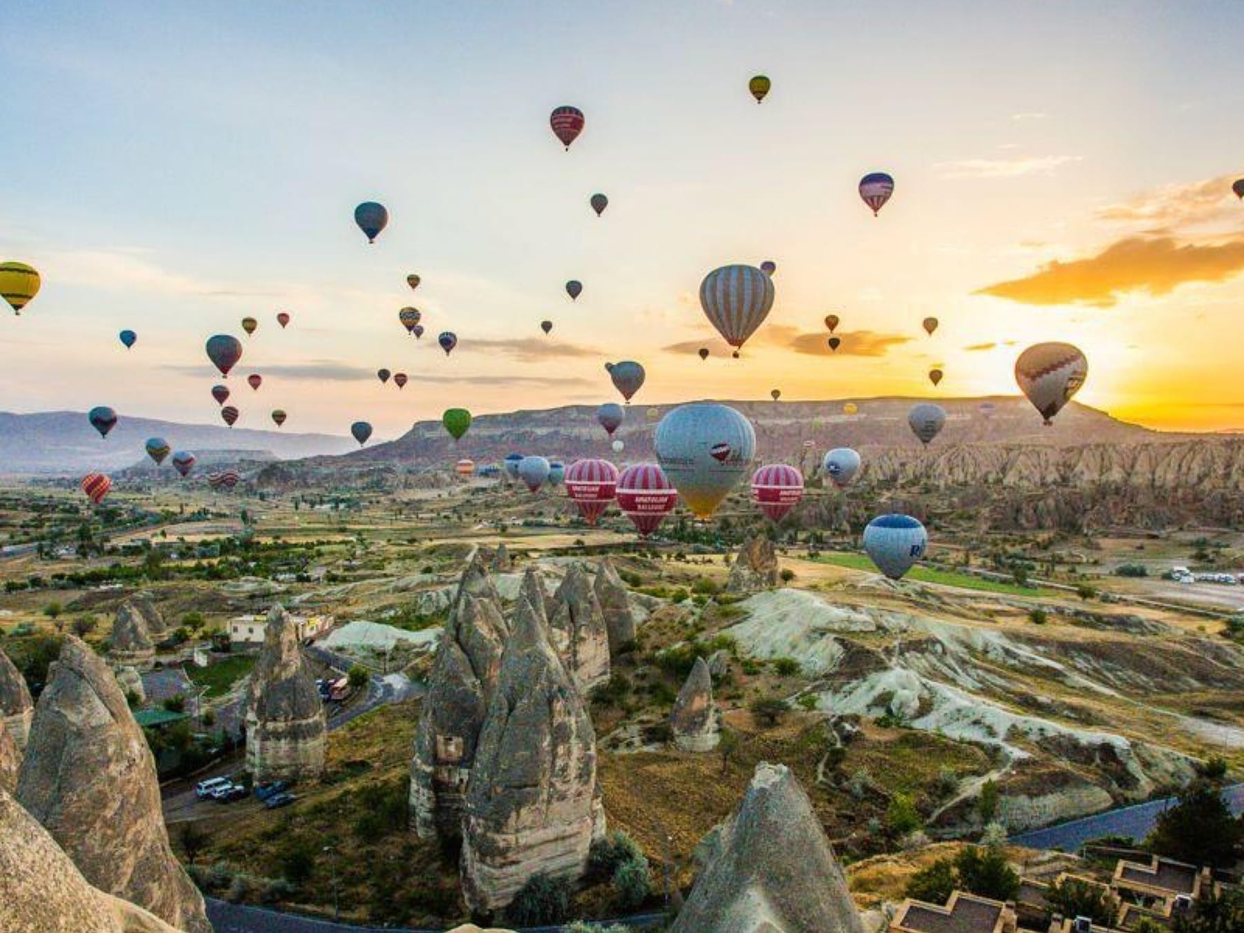 Hot-air balloons rising at sunrise over the fairy chimneys and cave dwellings of the Goreme valley in Cappadocia