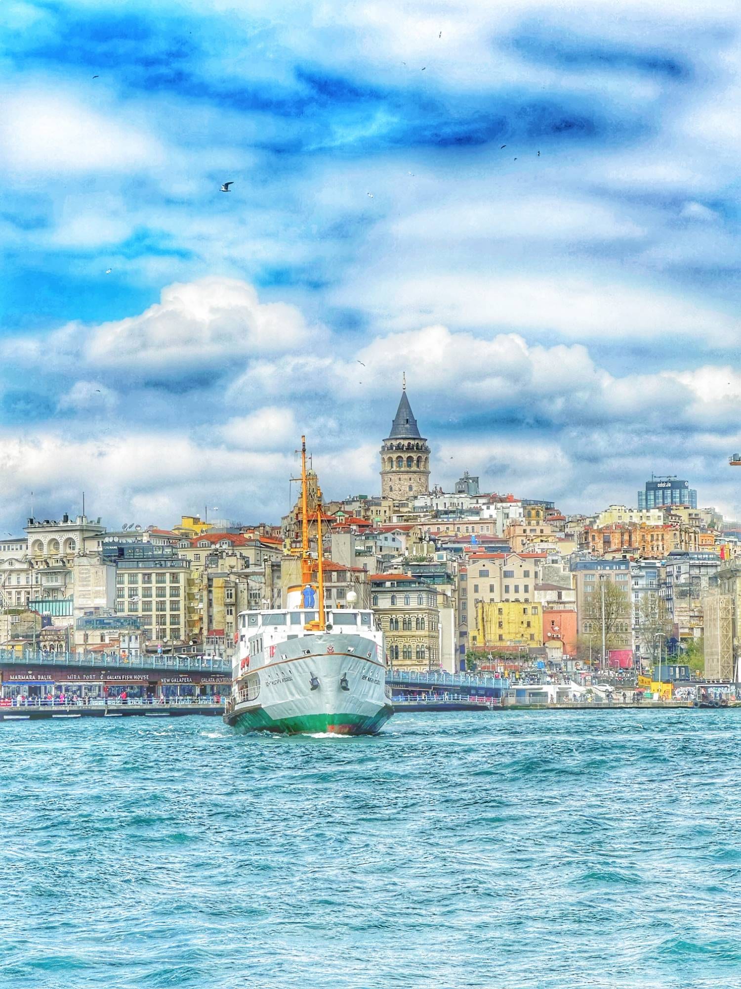 A classic Istanbul ferry crossing the water with the Galata Tower rising over the skyline