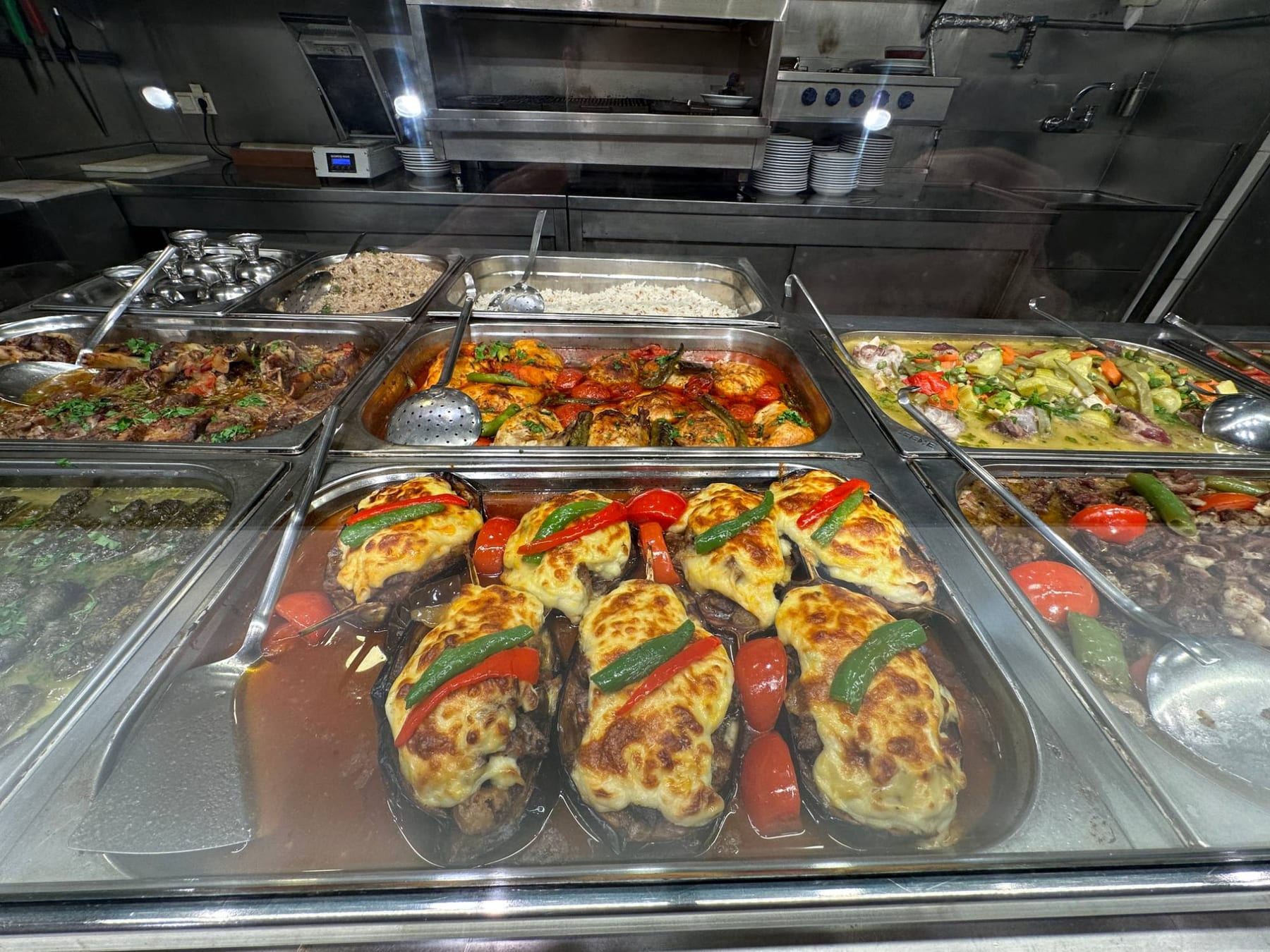A traditional Istanbul lokanta counter laden with home-style Turkish dishes — stuffed aubergine, chicken and vegetable stews and pilaf