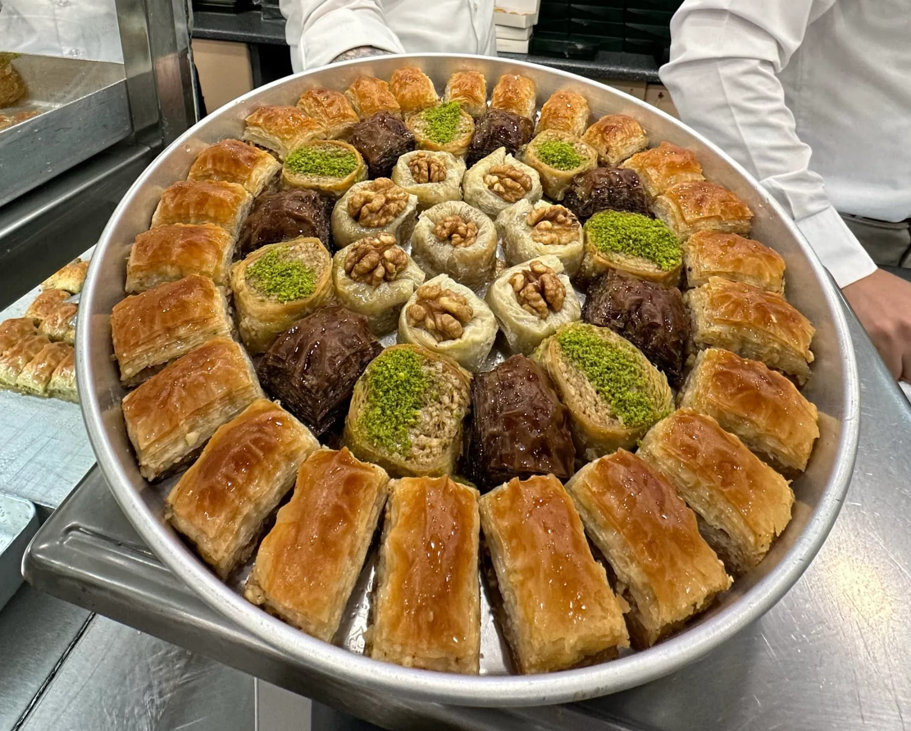 A large tray of freshly made Turkish baklava topped with pistachio and walnut at an Istanbul pastry shop