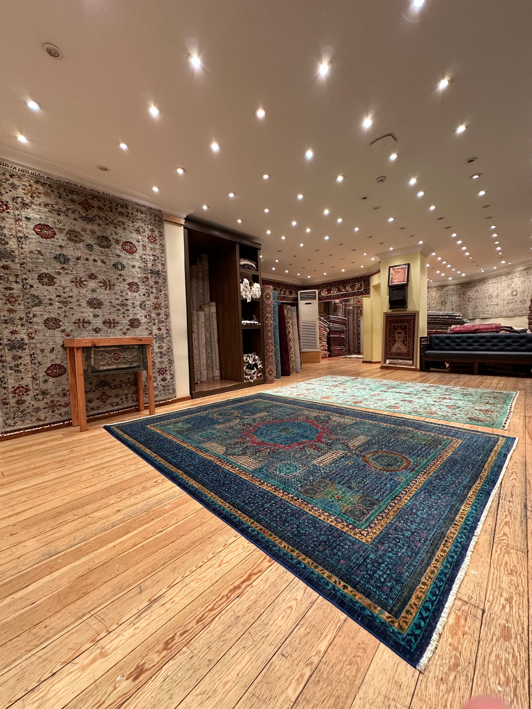 A hand-knotted blue Turkish carpet laid out on the wooden floor of a carpet showroom in Istanbul